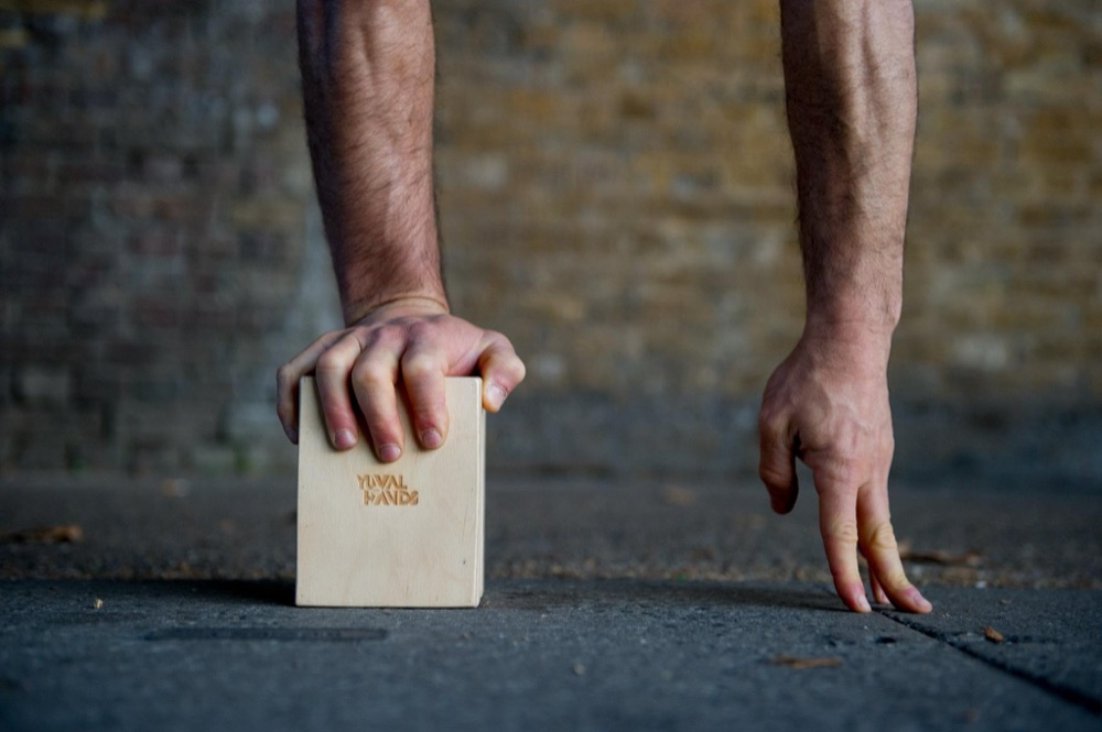 Hands gripping the YuvalOnHands Handstand Cube on the ground, ready for practice
